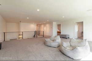 Sitting room featuring carpet, recessed lighting, and an upstairs landing