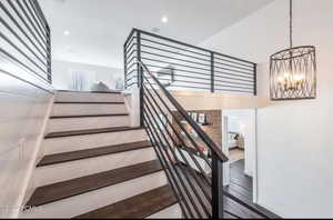 Stairs featuring wood finished floors, recessed lighting, and a chandelier