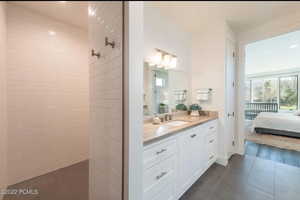 Ensuite bathroom featuring vanity, dark tile patterned flooring, a tile shower, and recessed lighting