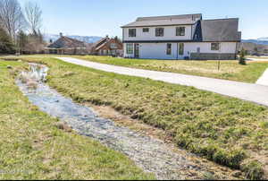 Back of house with a mountain view and a lawn