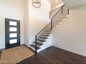Foyer entrance featuring stairway, dark wood finished floors, and a high ceiling