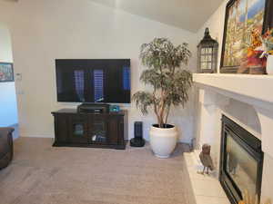 Living area with a tile fireplace, arched walkways, vaulted ceiling, and light colored carpet