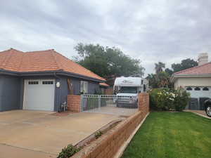 View of side of home featuring a tile roof, concrete driveway, stucco siding, and a garage
