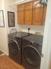 Laundry area with light wood-style floors, cabinet space, and independent washer and dryer
