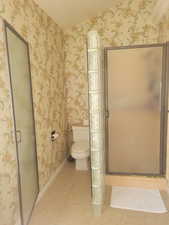 Bathroom featuring a stall shower, wallpapered walls, and light tile patterned floors