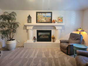 Carpeted living room with a tile fireplace and baseboards
