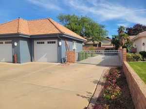 View of home's exterior with a gate, stucco siding, a tiled roof, and concrete driveway