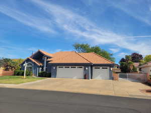 Ranch-style house with concrete driveway, a tile roof, stucco siding, and a garage