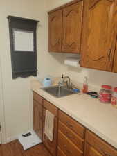 Kitchen featuring brown cabinetry, light countertops, and dark wood-style flooring