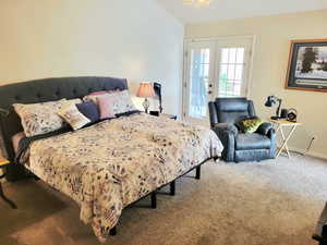 Carpeted bedroom featuring french doors, access to exterior, and vaulted ceiling