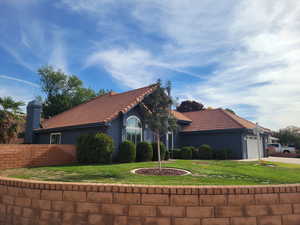 View of front facade featuring an attached garage, a tiled roof, stucco siding, concrete driveway, and a chimney