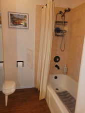 Bathroom with shower / bath combo with shower curtain and dark wood-style floors