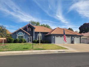 View of front of home featuring a front lawn, concrete driveway, stucco siding, a tile roof, and an attached garage