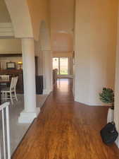 Corridor featuring arched walkways, wood finished floors, and a high ceiling