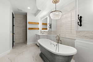 Full bathroom featuring vanity, a soaking tub, recessed lighting, marble finish flooring, and a chandelier