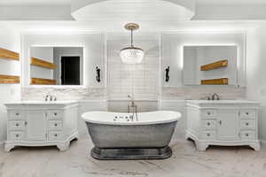 Full bath featuring a soaking tub, two vanities, a chandelier, and tasteful backsplash