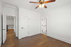 Unfurnished bedroom featuring dark wood finished floors, attic access, and ceiling fan