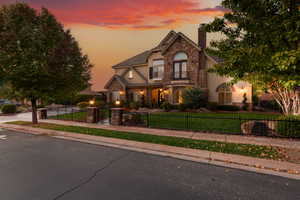 Traditional-style house featuring stucco siding, a chimney, stone siding, a fenced front yard, and a gate