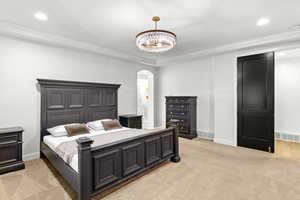 Bedroom with recessed lighting, light colored carpet, arched walkways, ornamental molding, and a textured ceiling