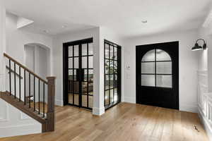 Entrance foyer featuring light wood-style floors, a textured ceiling, arched walkways, recessed lighting, and stairway
