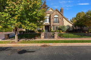 View of front of house featuring a gate, a fenced front yard, a chimney, stone siding, and stucco siding