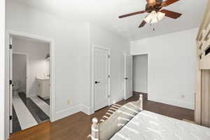 Bedroom featuring dark wood-style floors, a ceiling fan, and connected bathroom