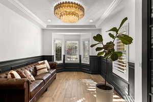 Sitting room with a chandelier, light wood-style floors, a textured ceiling, a raised ceiling, and ornamental molding