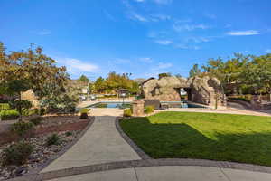 View of grassy yard with an outdoor pool and a patio