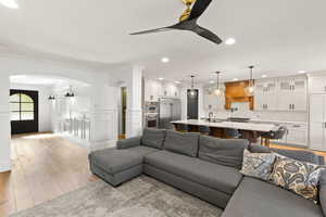 Living area featuring arched walkways, light wood-type flooring, recessed lighting, ceiling fan, and a decorative wall