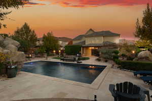 Pool at dusk featuring a patio, an outdoor pool, and a hot tub