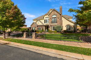 View of front facade with stucco siding, a gate, a fenced front yard, and a chimney