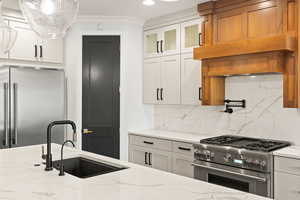 Kitchen with high end appliances, light stone countertops, decorative backsplash, white cabinetry, and recessed lighting