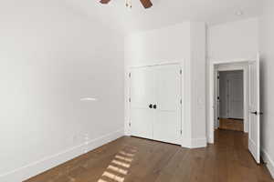 Unfurnished bedroom featuring dark wood-style flooring, a closet, and ceiling fan