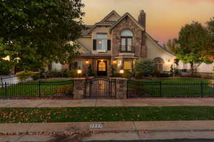 View of front facade featuring a gate, stucco siding, stone siding, and a balcony