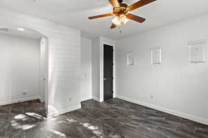 Unfurnished bedroom featuring arched walkways and ceiling fan