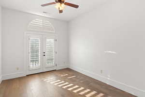 Empty room featuring french doors, hardwood / wood-style flooring, and a ceiling fan