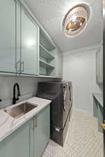 Washroom with cabinet space, a textured ceiling, washer and dryer, and light tile patterned floors