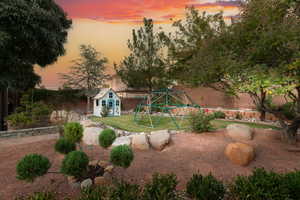 Fenced backyard featuring a playground and an outdoor structure