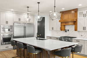 Kitchen with a breakfast bar area, light wood finished floors, light stone counters, glass insert cabinets, and white cabinetry