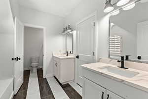 Full bath with two vanities and dark tile patterned floors