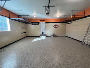 Immaculate garage with epoxy flooring and overhead storage.