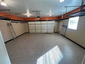 Garage featuring baseboards, automatic door and man door.