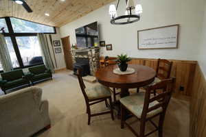 Dining room with lofted ceiling, wooden ceiling, carpet, a chandelier, and a wood stove