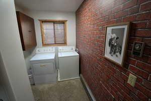 Laundry room with brick wall and separate washer and dryer