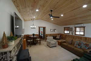 Living area featuring wood walls, a wainscoted wall, vaulted ceiling, wood ceiling, and light carpet