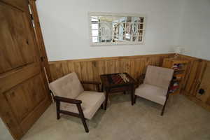 Sitting room featuring wainscoting, wooden walls, and light colored carpet