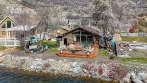 Back of house with a deck with water view and a chimney
