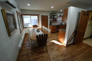 Dining space featuring dark wood-style floors, a wall unit AC, a baseboard heating unit, and recessed lighting