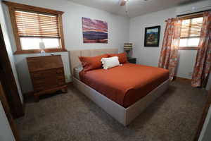 Carpeted bedroom featuring a wall mounted AC and ceiling fan