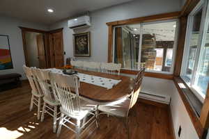 Dining room with dark wood-style flooring, a wall mounted air conditioner, baseboard heating, and recessed lighting